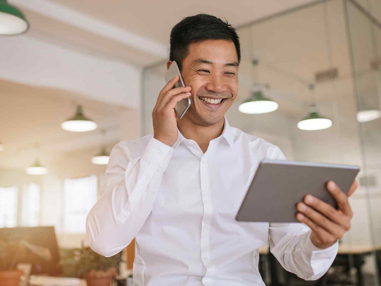 Mann im Büro telefoniert und hält dabei ein Tablet